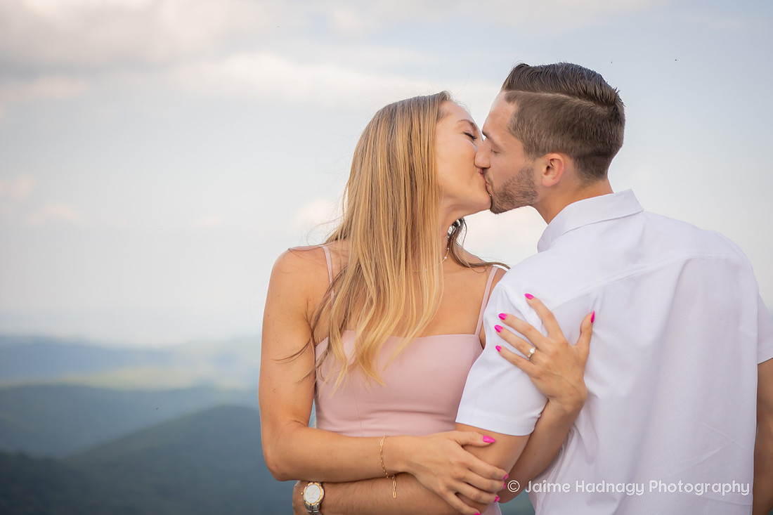 Engaged Couple Kissing with Mountains Behind