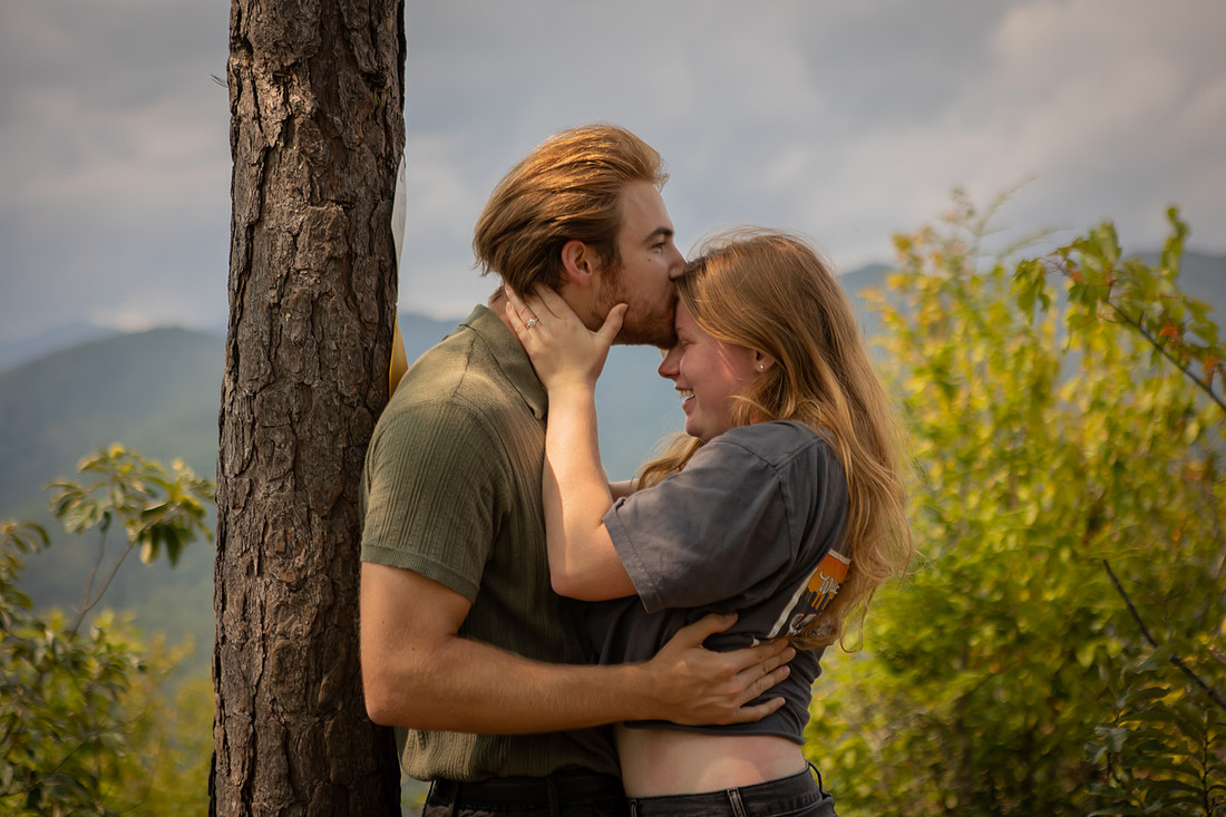 Young Couple in Nature with Man Kissing Woman's Forehead