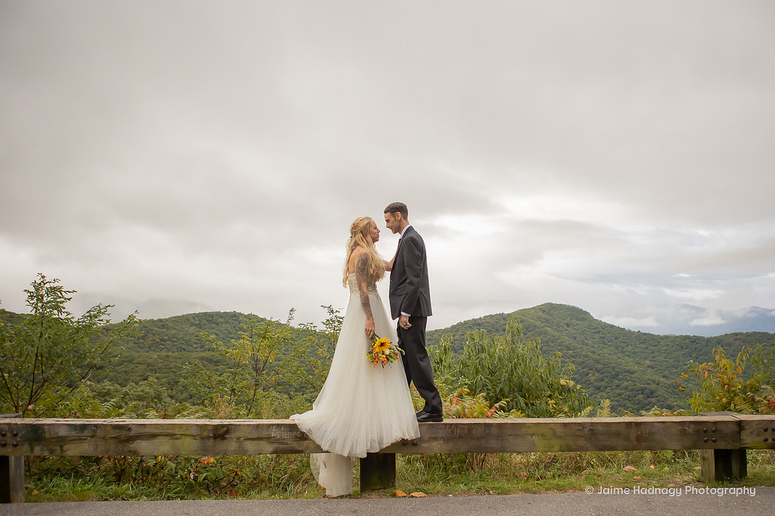 Bride and Groom walking on a Guard Rail on Blue Ridge Parkway | Asheville Wedding Photographer