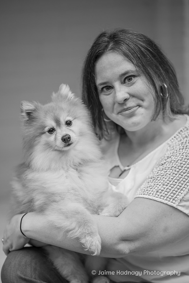 A woman holding her pomeranian dog in black and white