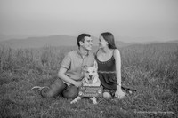 black and white photo of a couple with their dog wearing a sign that says my humans are getting married
