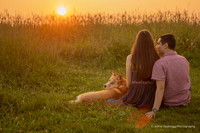 couple watching the sunset with their dog