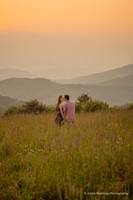 couple kissing at sunset in a field in the mountains