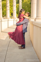 man lifting a woman wearing a maroon dress into the air during an engagement photoshoot