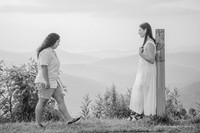 Black and white photo of a woman approaching another woman in the mountains
