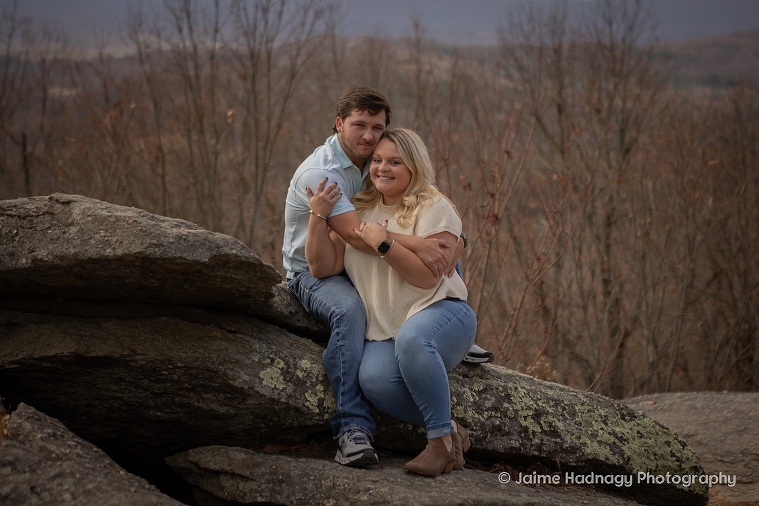 Engaged Couple Snugging on Boulders in the Mountains